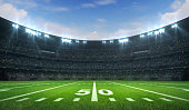 istock American football league stadium with white lines and fans, daytime side field view 1176737230