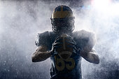 istock American football player in a haze and rain on black background. Portrait 981824222