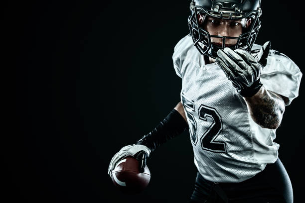 American football sportsman player in helmet isolated on black background. Sport and motivation wallpaper. American Football player on stadium with smoke and lights. american football player stock pictures, royalty-free photos & images