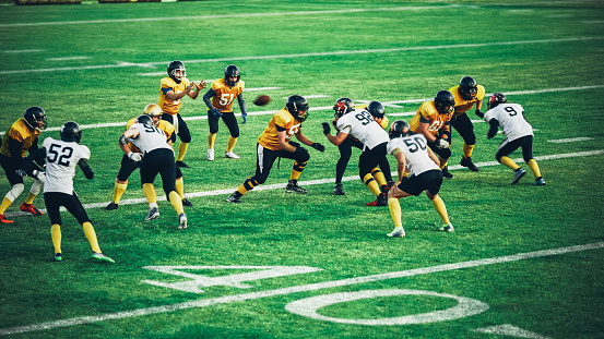 American Football Teams Start Game: Professional Players, Aggressive Face-off, Tackle, Pass, Fight for Ball and Score. Warrior Competition Full of Brutal Energy, Power, Skill.