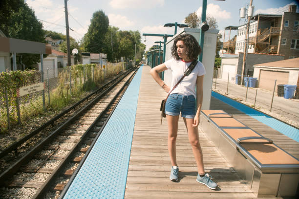 American Millennial Hispanic Woman Waits for Train Chicago Illinois A millennial Puerto Rican woman in her 20's waits on a train station platform as she travels locally in Chicago, Illinois with public transportation. She looks down the tracks of the elevated train. Photographed on warm fall day that feels like summer. Full frame shot with a Nikon D800 DSLR camera. hot puerto rican woman stock pictures, royalty-free photos & images