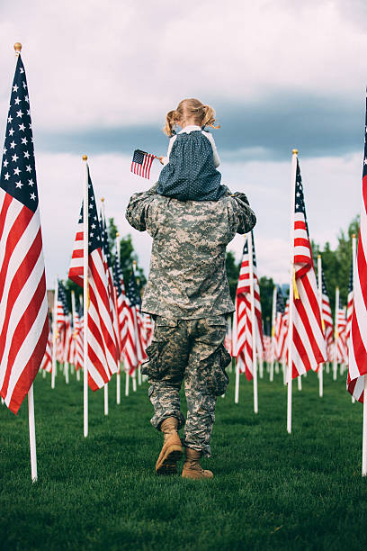 American soldier walking with his daughter on his shoulders stock photo