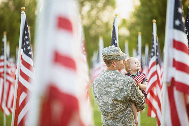 American soldier with daughter American soldier looking at flags with his daughter memorial day stock pictures, royalty-free photos & images