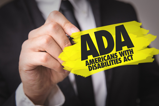 Person holding sign with "ADA" Americans with Disabilities Act.