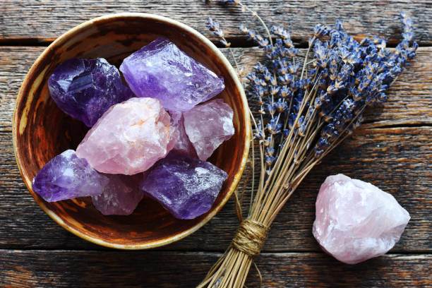 Amethyst and Rose Quartz Healing Crystals A table top image of a pottery bowl with large rose quartz and amethyst crystal with dried lavender flowers. rose quartz stock pictures, royalty-free photos & images