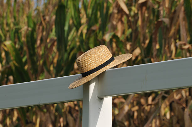 Amish straw hat laying over fence post stock photo