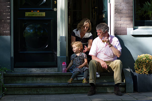 amsterdam, holland: family on front stoop with drinks - pensioen nederland stockfoto's en -beelden