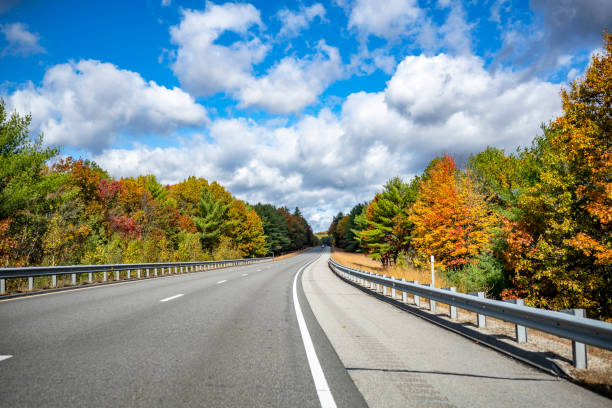 An alluring landscape with a highway stretching into the horizon framed by picturesque autumn maples in the state of Massachusetts stock photo