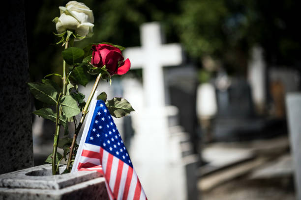 an american flag is seen on the grave of a veteran. - covid cemiterio imagens e fotografias de stock