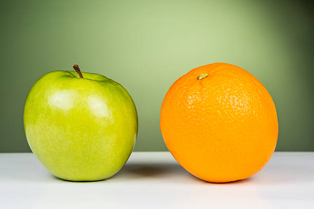 An apple sitting next to an orange stock photo