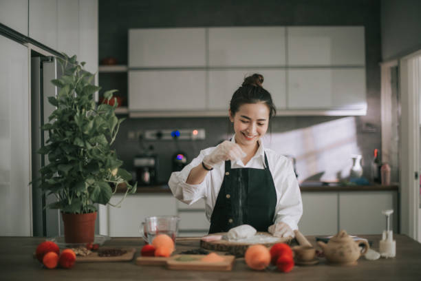 eine asiatische chinesische schöne frau macht chinesische traditionelle mitte herbst schnee haut mondkuchen in ihrer küche - asiatischer koch stock-fotos und bilder
