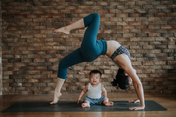 an asian chinese female yoga instructor with bridge pose while her son looking at camera  asian yoga pants stock pictures, royalty-free photos & images