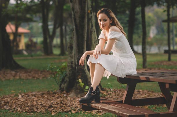 an asian female teenager girl sitting on the park bench portrait an asian female teenager girl sitting on the park bench portrait girls in very short dresses stock pictures, royalty-free photos & images