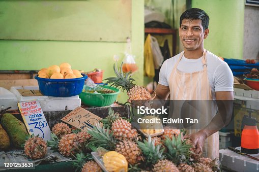 istock An asian fruit shop owner examining and choosing a good quality pineapple to his customer 1201253631