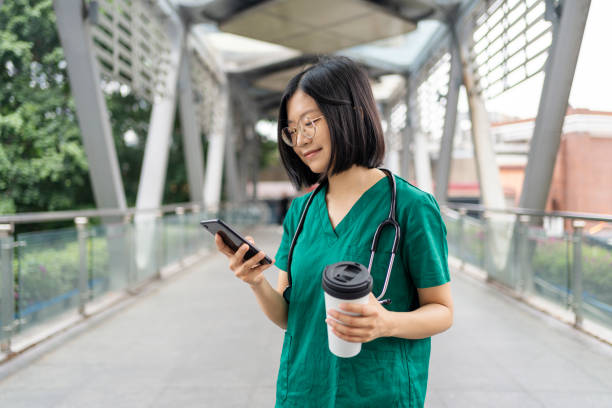 An Asian nurse using mobile phone for digital banking stock photo