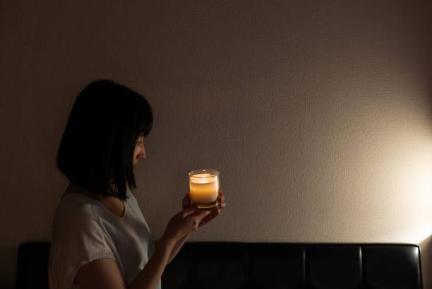 An Asian woman stares at candlelight in her home at night. stock photo