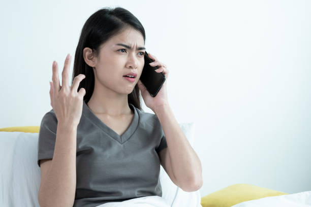 An Asian woman talking to someone on a mobile phone, She expressed dissatisfaction. stock photo