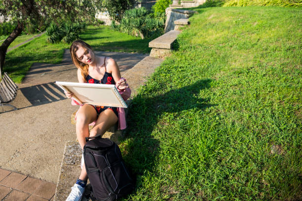 An attractive, young female artist paints a picture in the park stock photo