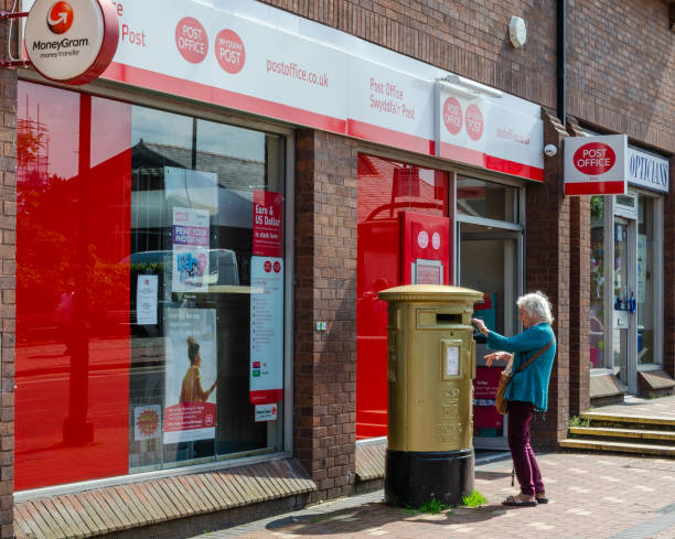 An elderly lady uses a post box. stock photo