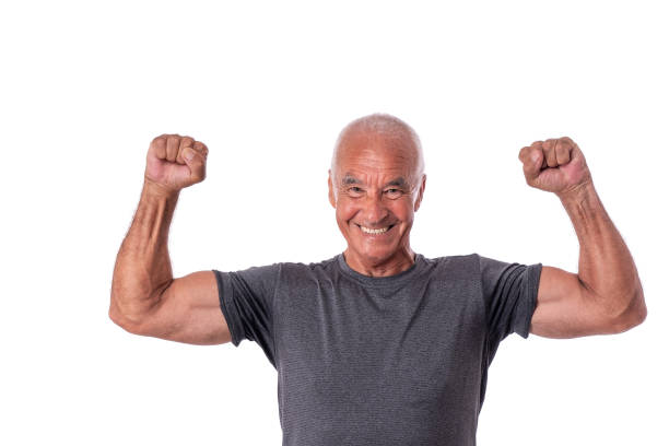An elderly man, an athlete in excellent physical shape, celebrates a victory with cheerful emotions. On a white isolated background. stock photo