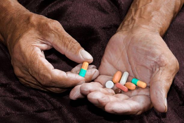An elderly man holds a lot of colored pills in old hands. Painful old age. Health care of older people. Top View stock photo