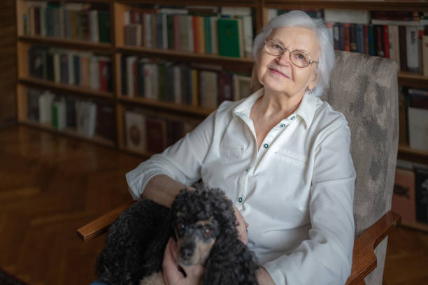 An elderly woman sitting in a chair with her pet stock photo