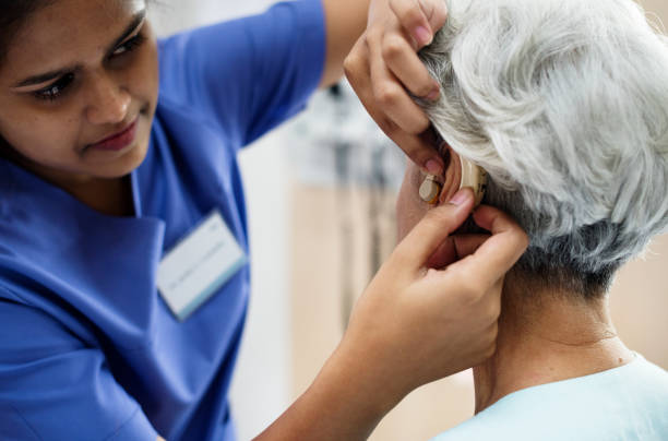 yaşlı bir kadın ile işitme cihazı - hearing aid stok fotoğraflar ve resimler