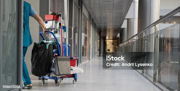 istock An employee pulls a trolley for cleaning offices. Woman cleaner is engaged in work. 1316473356