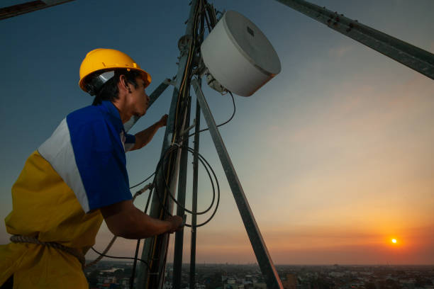An engineer is working on height using a safety helmet and equipment fixing an antenna stock photo