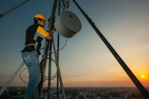 An engineer is working on height using a safety helmet and equipment fixing an antenna stock photo