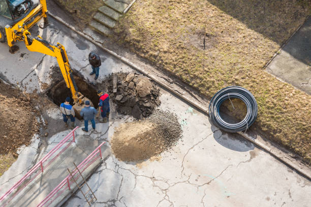 An excavator digs a trench to repair a pipeline on a city street stock photo