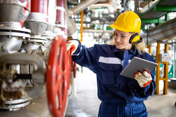 An experienced refinery or factory worker checking pressure of gas pipes. An experienced refinery or factory worker checking pressure of gas pipes. oil refinery factory stock pictures, royalty-free photos & images