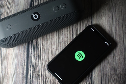 An iphone 11 screen showing spotify icon with beats pill speaker beside it