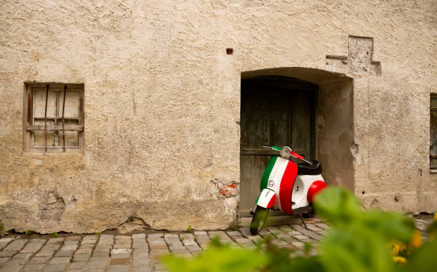 An old bike in italian tricolor livery parked near old wall. Stylish background for travel theme designs. Lagre copy space on left stock photo