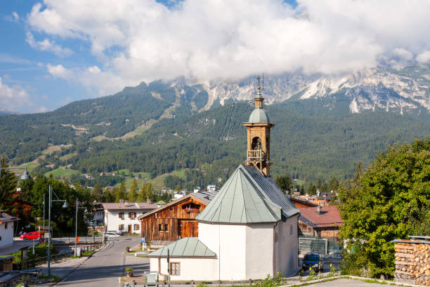 An old chapel in an alpine town amid a mountain peak in dense clouds, Cortina D'Ampezzo, Italy stock photo
