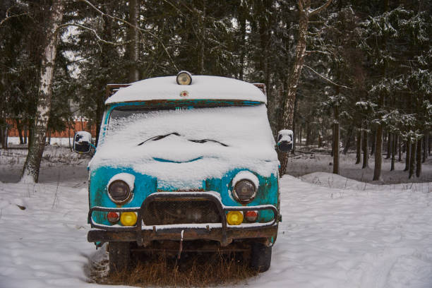 een oud roestig ambulancebusje bevindt zich in een sneeuw-behandelde open plek op een bewolkte de winterdag. - front view old jeep stockfoto's en -beelden