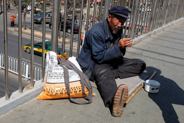 An old street beggar beggs for momey on a pedestrian overpass. stock photo