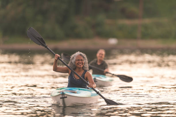 ett äldre par njuta av en sen kväll i kajak på floden - woman kayaking bildbanksfoton och bilder