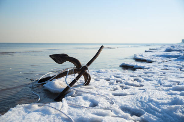 An patinous anchor alongside frozen seashore in winter stock photo