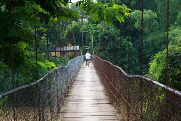 An unidentified man is crossing the bridge with a bicycle. stock photo