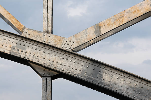 An up close image of the beams holding up a steel bridge Detail of steel bridge in front of blue sky girder stock pictures, royalty-free photos & images