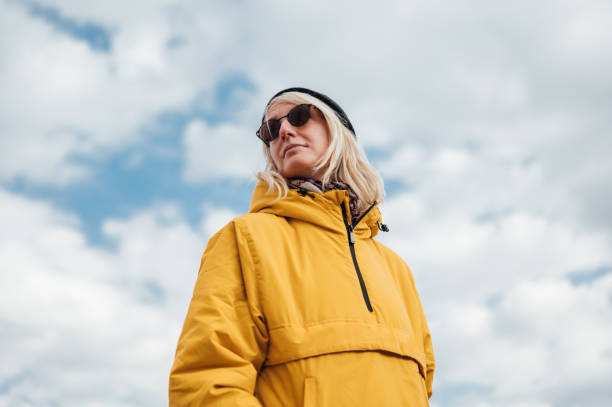 An urban young woman in yellow jacket against blue sky 1 stock photo