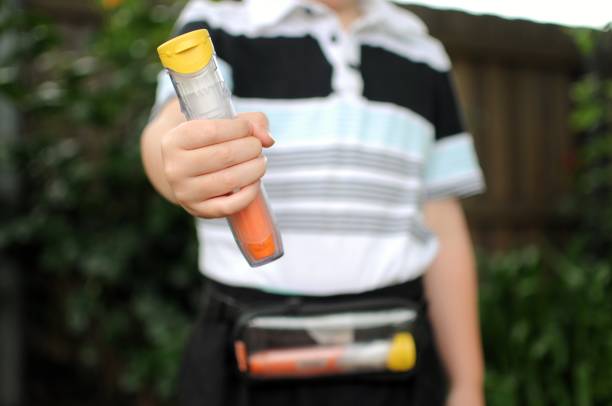 Anaphylaxis Auto injectors in Carry Case Child holding a anaphylaxis Auto injector with one also in small pouch. Carry case is being worn by a child. adrenaline stock pictures, royalty-free photos & images