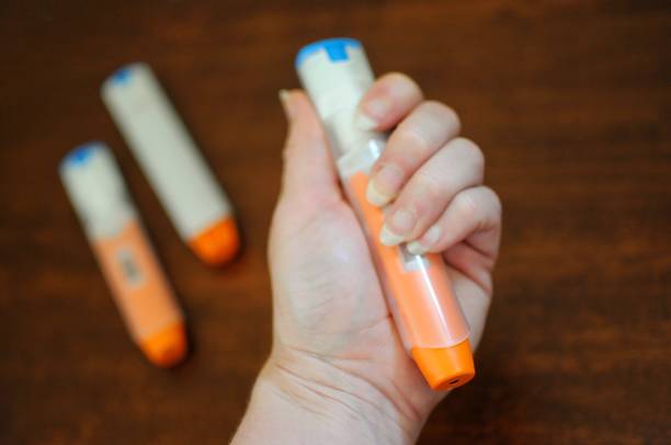 Anaphylaxis Auto Injectors Woman’s hand holding a unused epinephrine Auto injector. The device is commonly used to treat the life threatening immune response known as anaphylaxis. adrenaline stock pictures, royalty-free photos & images