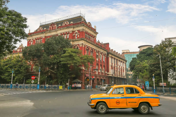 Ancient colonial architecture building with famous yellow cab on city road crossing at Kolkata India stock photo