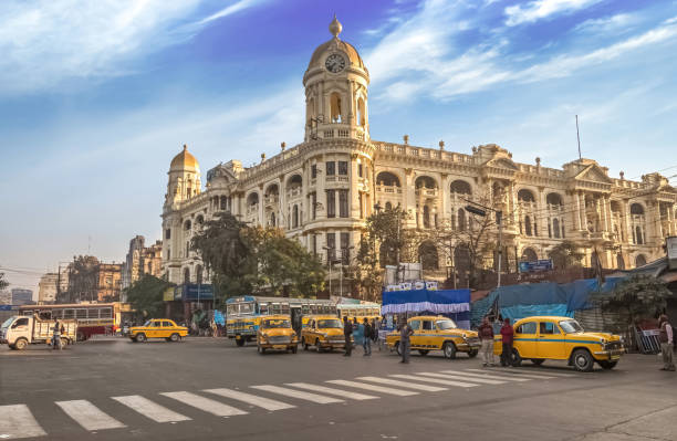 Ancient colonial city architecture building with famous yellow taxi on city road crossing at Kolkata India stock photo