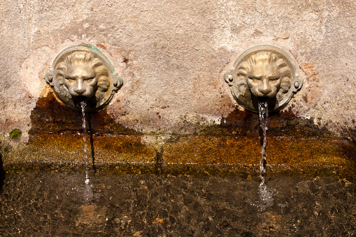 Close-up view of ancient A Burga hot spring water fountain, built in the historic Caldas de Reis old town in 1881, featuring two lion heads.  Thermalism in  Pontevedra province, Galicia, Spain.