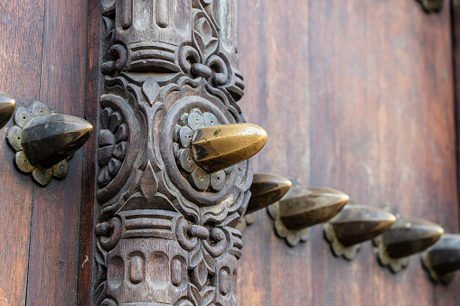 Close up of a ancient traditional wooden carved door with ornaments and bronze spike in Stone Town on island Zanzibar, Tanzania, East Africa