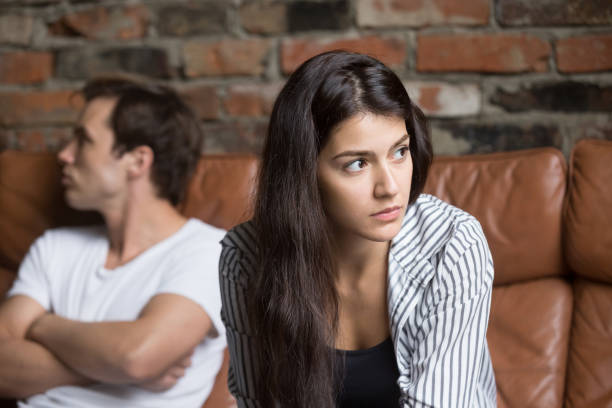Angry couple avoiding talking after family fight Angry unhappy young couple ignoring not looking at each other after family fight or quarrel, upset thoughtful spouses avoiding talk, sitting silently on couch, having relationship troubles. ignoring stock pictures, royalty-free photos & images