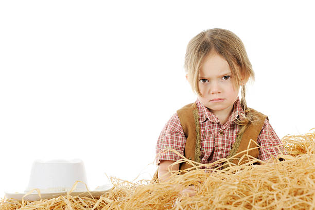 Angry Little Cowgirl An angry preschool cowgirl sitting behind a pile of hay with her hat nearby.  On a white background with space for your text over her hat. hats off to you stock pictures, royalty-free photos & images